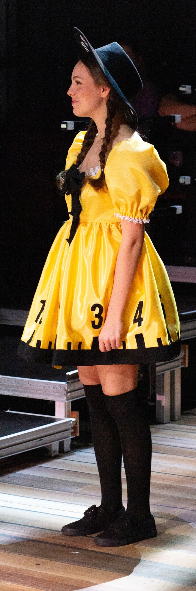 A performer in a yellow costume stands beside the stage.