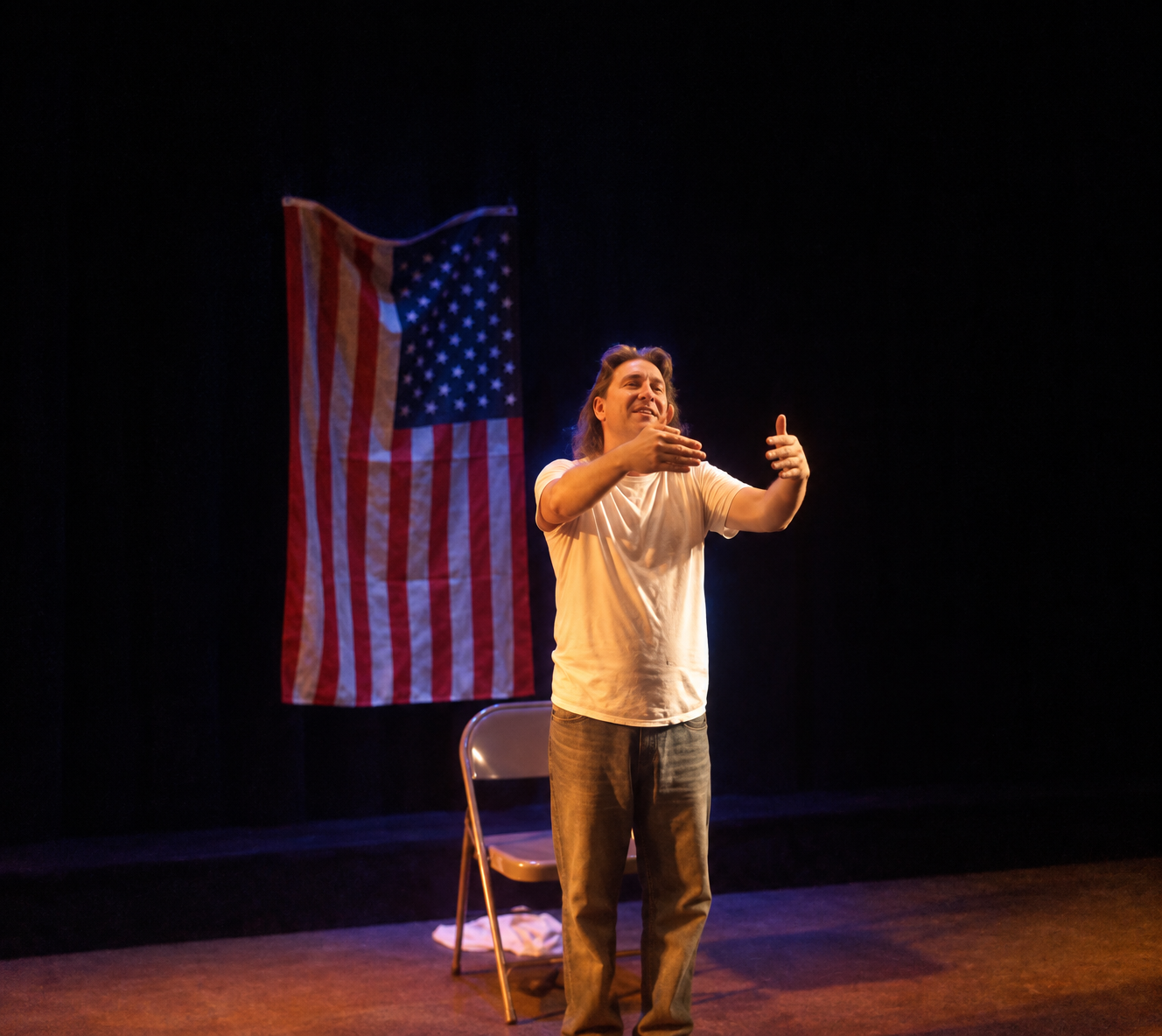 Manuel Simons performing onstage beside an American flag and a chair