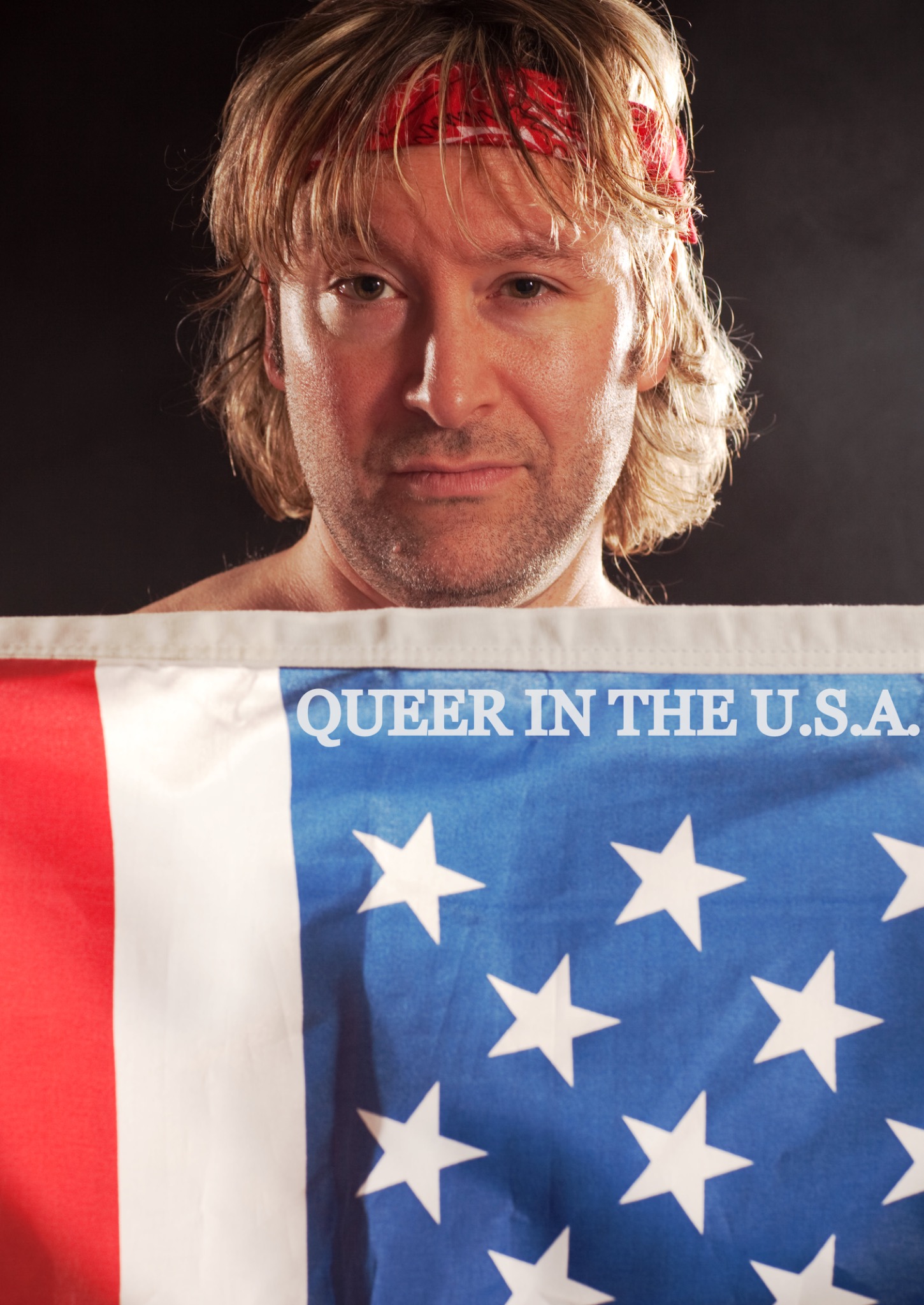 The performer looks directly ahead above a flag bearing the title Queer in the U.S.A.