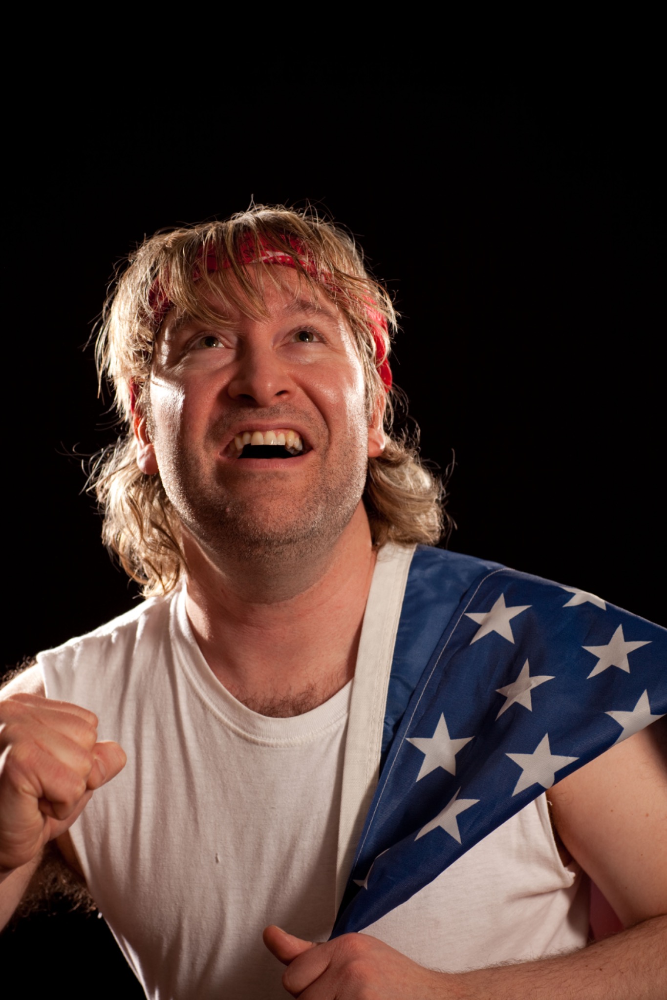 The performer looks upward with an animated expression, a star-spangled cloth across one shoulder